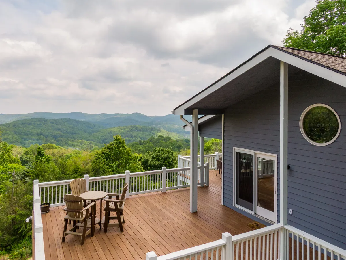 A spacious wooden deck overlooks sweeping mountain views, with comfortable outdoor seating inviting guests to relax and enjoy the scenery. The serene environment makes it an ideal spot for sipping morning coffee, sharing a sunset, or stargazing as a couple.
