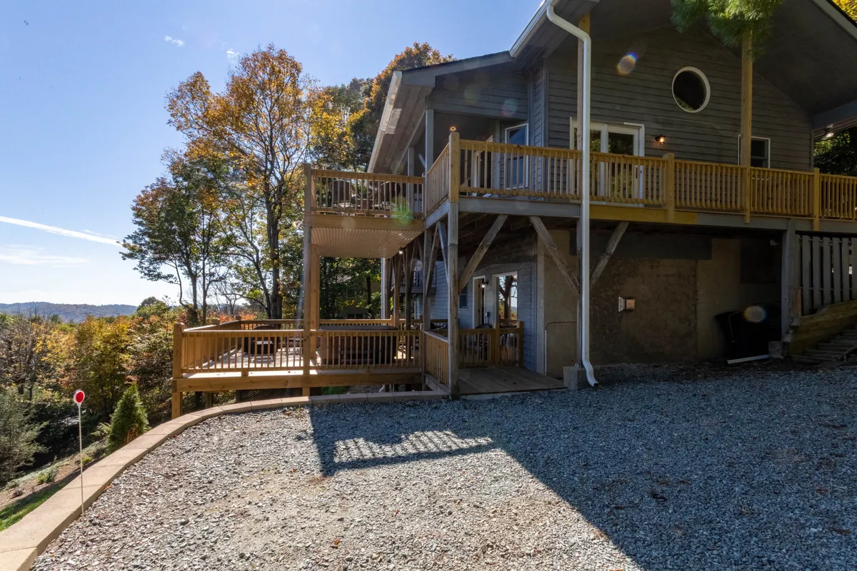 A wide view of the deck set among lush trees with panoramic mountain vistas. This outdoor space is perfect for enjoying nature, relaxing with pets, or starting the day with coffee in the fresh mountain air.