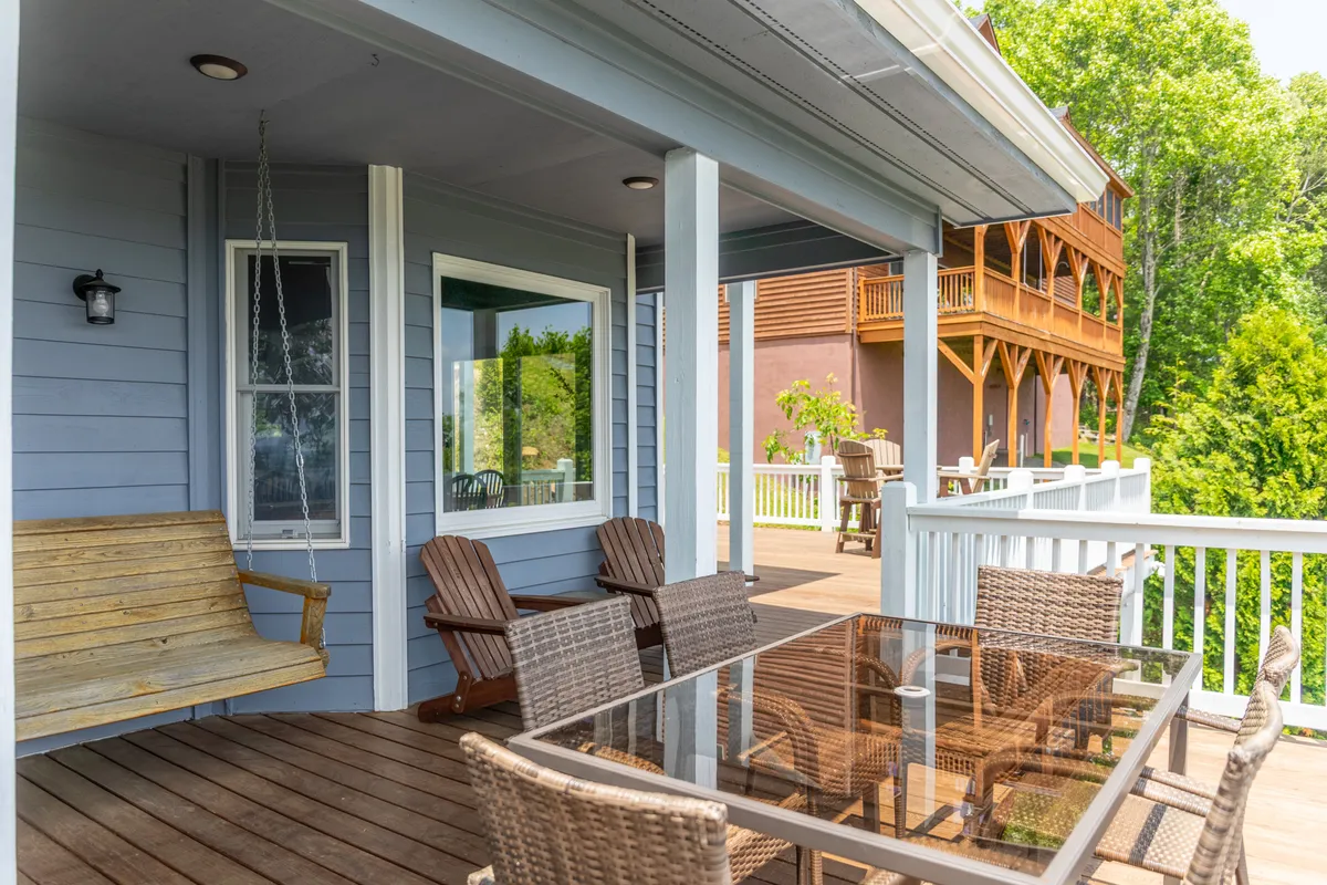 An exterior view of the main deck featuring an outdoor dining table, a classic swing bench, and lush greenery—offering a seamless transition from indoor comfort to savoring the crisp mountain air and stunning vistas.