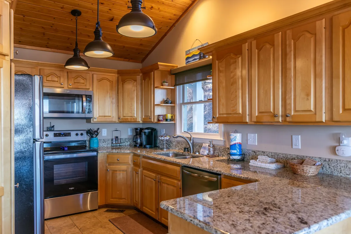 A close-up of the kitchen's granite countertop, stainless steel appliances, and wooden cabinetry—ideal for showcasing the space where meals and morning rituals with a Keurig begin.