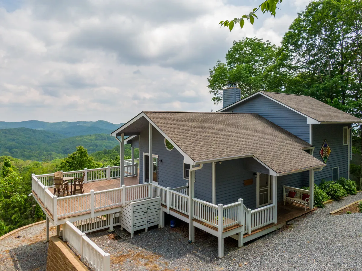 This image showcases a spacious deck with comfortable seating, perfectly positioned to take in breathtaking mountain views. The house's architecture is visible, blending with the natural surroundings, and the space is ideal for gatherings, meals, or simply soaking up the scenery.