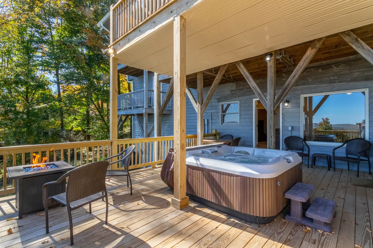 This exterior image features a hot tub, a fire pit, and ample outdoor seating, all set against a peaceful natural backdrop. The setup suggests a perfect space for groups to relax together after a day of exploring, with both the hot tub and fire pit inviting social gatherings beneath the stars.