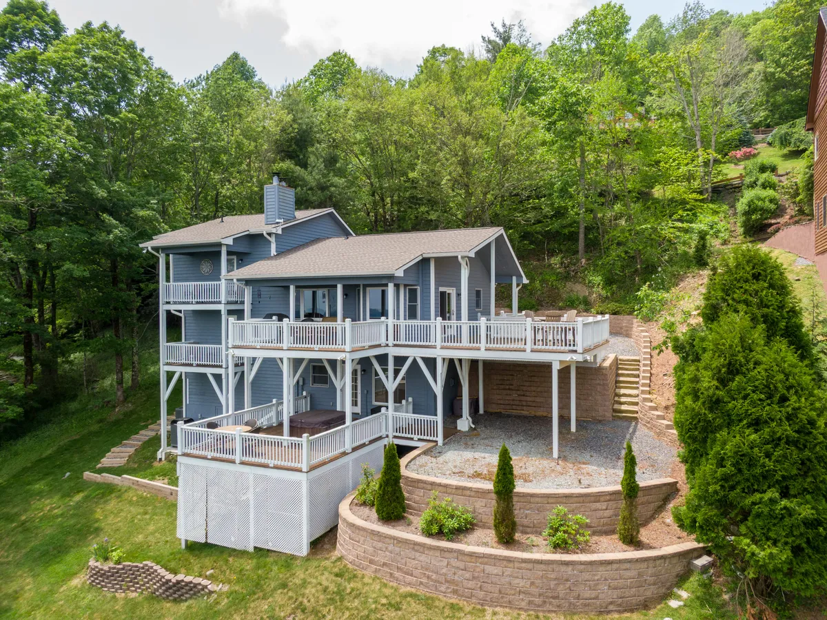 The image showcases a beautiful multi-level deck surrounded by lush greenery and elegant stone landscaping. The expansive decks offer ample space for outdoor gatherings, relaxing in the fresh mountain air, and enjoying panoramic views of the Blue Ridge Mountains, all set against a backdrop of serene natural beauty.