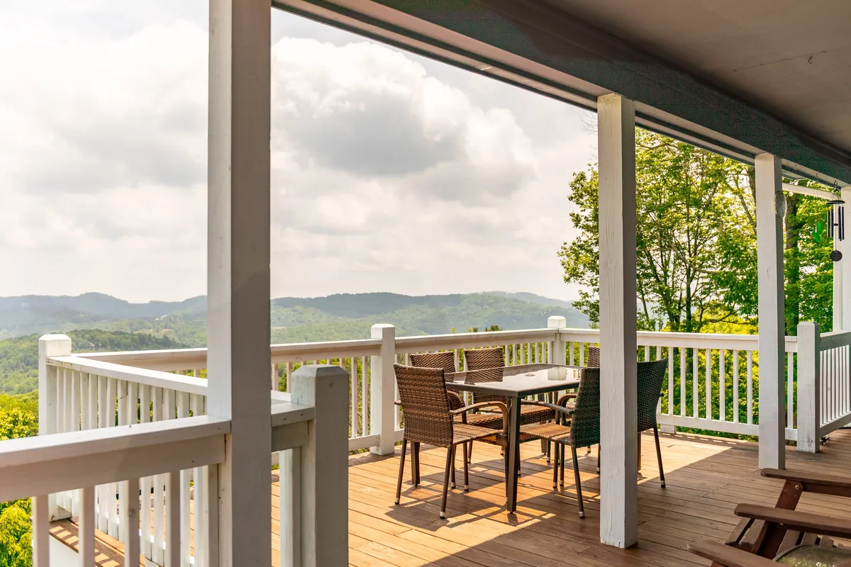 A tranquil outdoor seating area is set on a deck overlooking expansive mountain views. The table with chairs invites guests to relax, socialize, or enjoy meals with the stunning natural backdrop. The setting is peaceful, ideal for moments of reflection or gathering after a day of adventure.