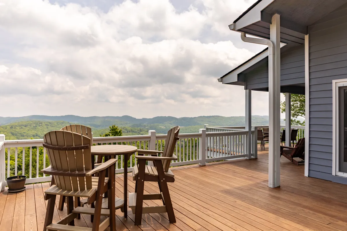 This image displays a spacious wooden deck outfitted with Adirondack chairs, inviting guests to sit back and soak in the sweeping scenic mountain views. The setting conveys a tranquil outdoor living space perfect for relaxing mornings or friendly conversations at sunset.